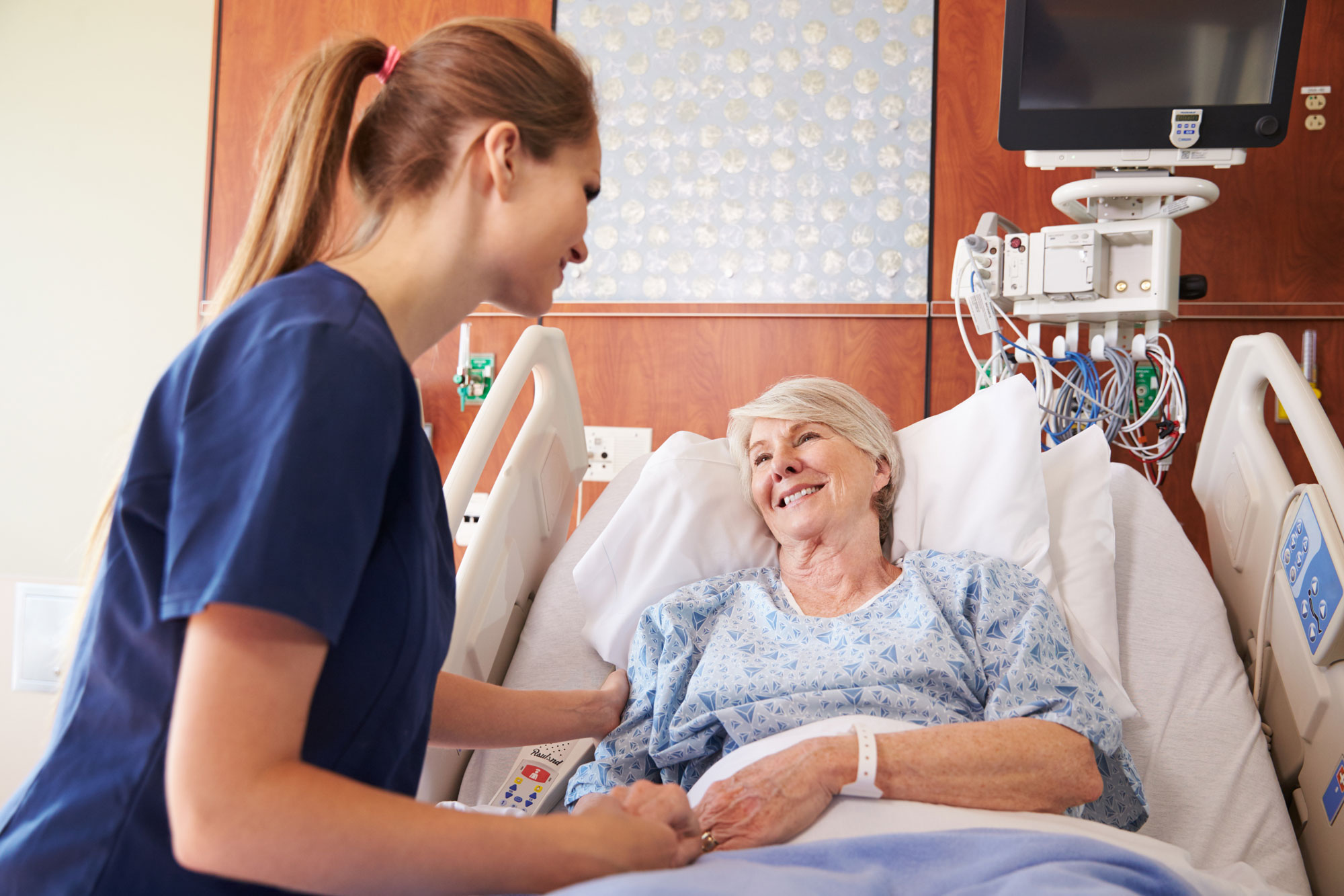 A female nurse is tending to an elderly patient