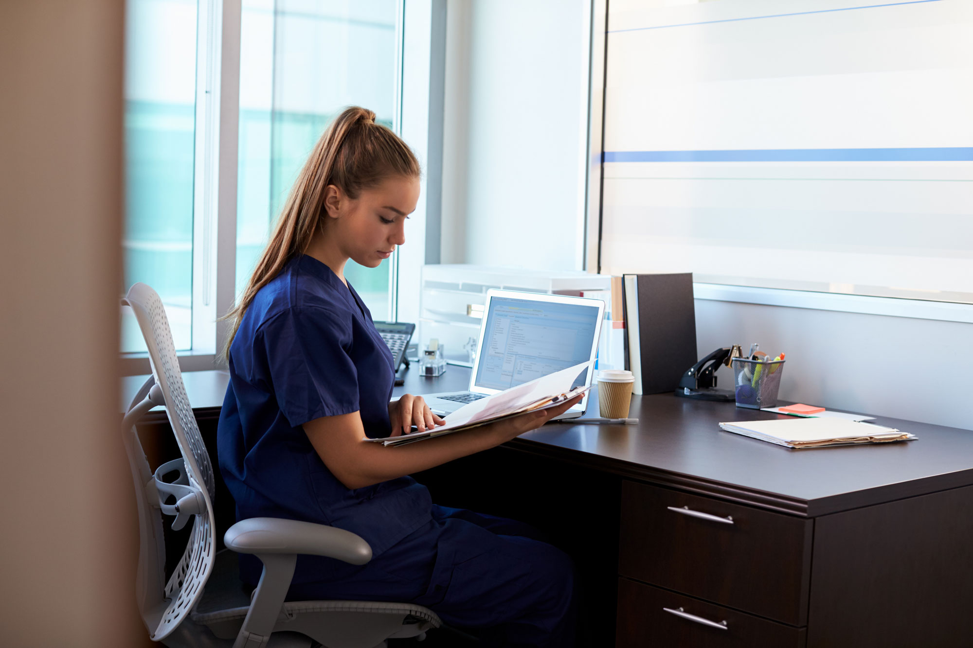 A young female nursing student is studying on her laptop