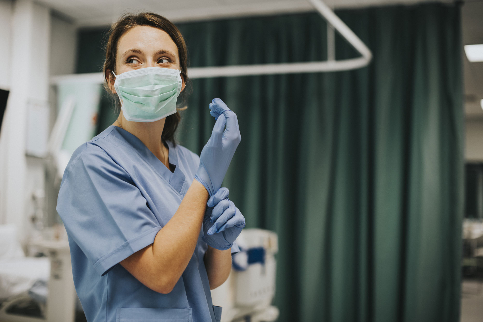 A female registered nurse is putting on medical gloves