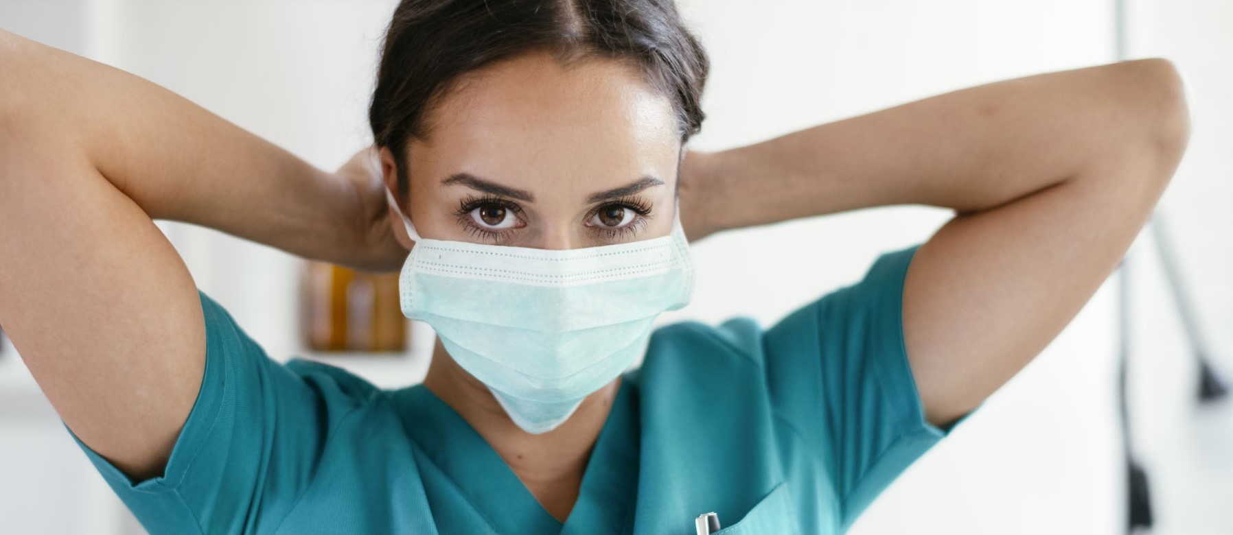 A female licensed practical nurse is wearing scrubs and a mask