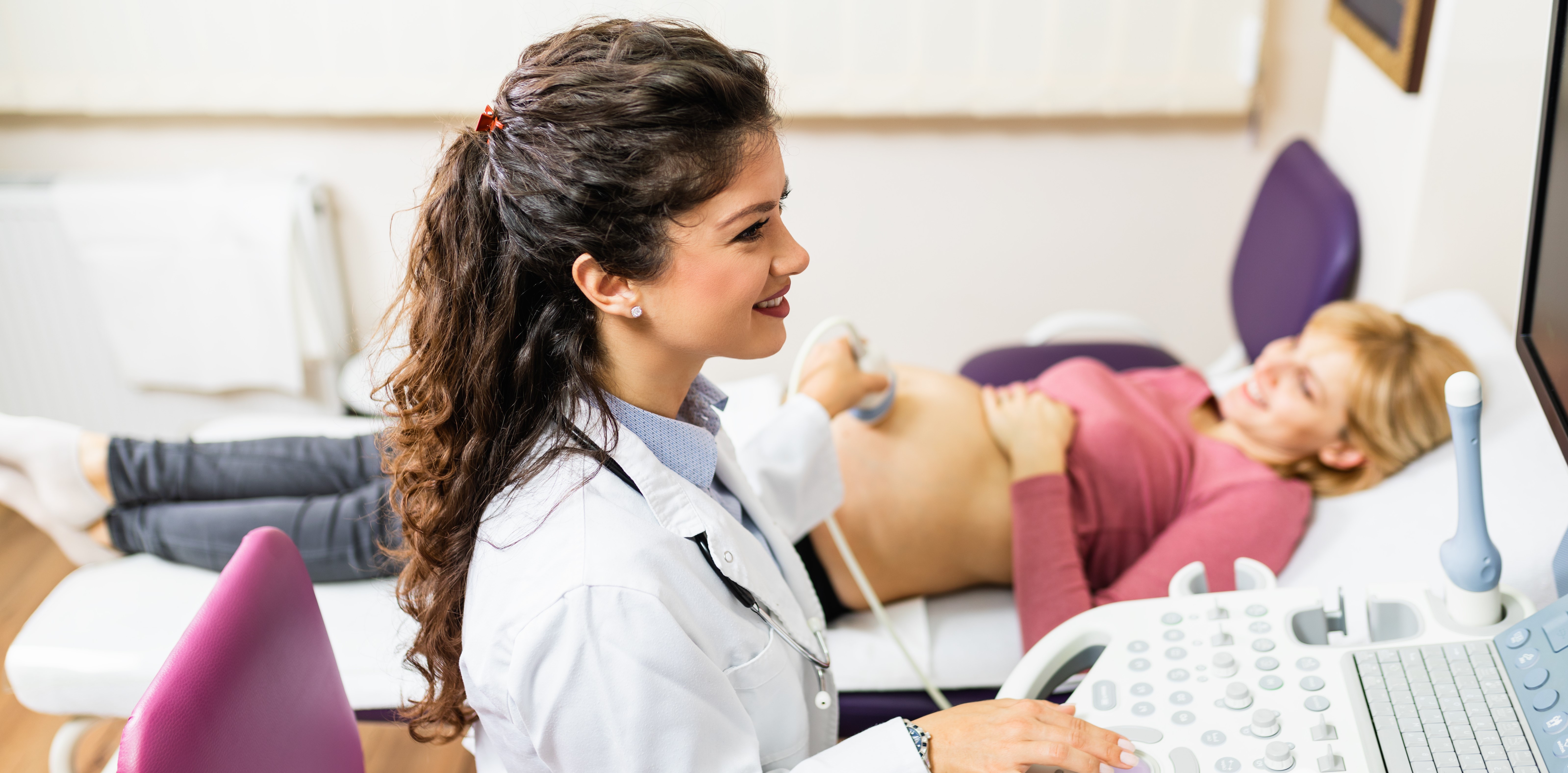 Obstetrician examining pregnant belly by ultrasonic scan.